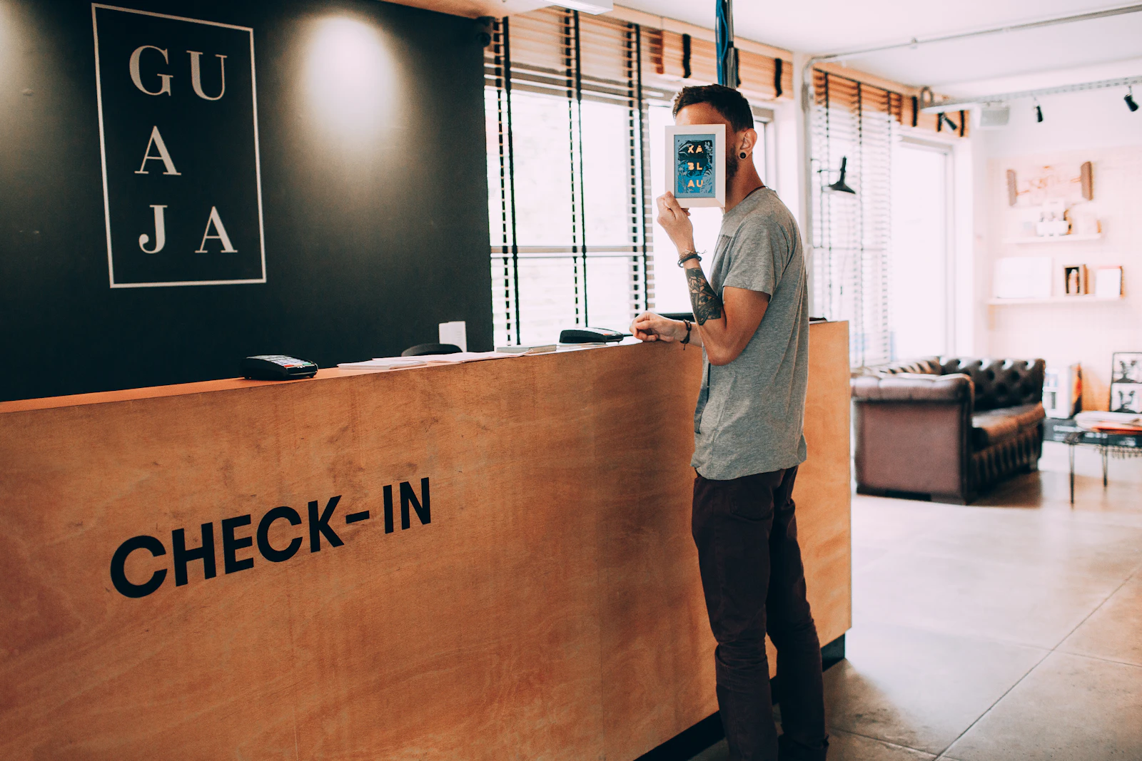 A guest standing at a wooden hotel check-in counter in a bright lobby