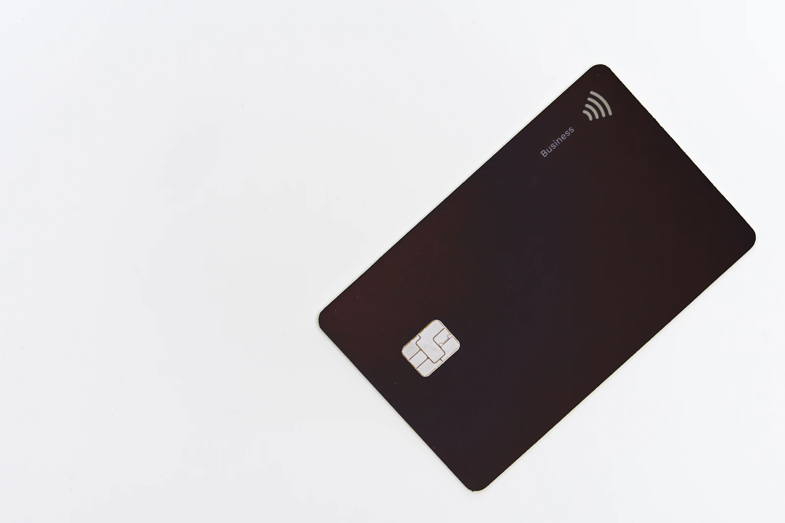A dark credit card with a chip lying on a white surface
