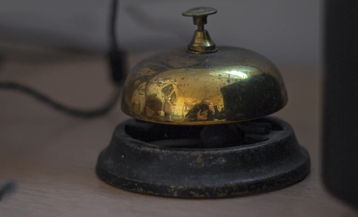 A vintage brass service bell on a wooden desk