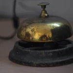 A vintage brass service bell on a wooden desk