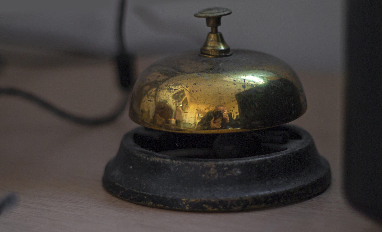 A vintage brass service bell on a wooden desk