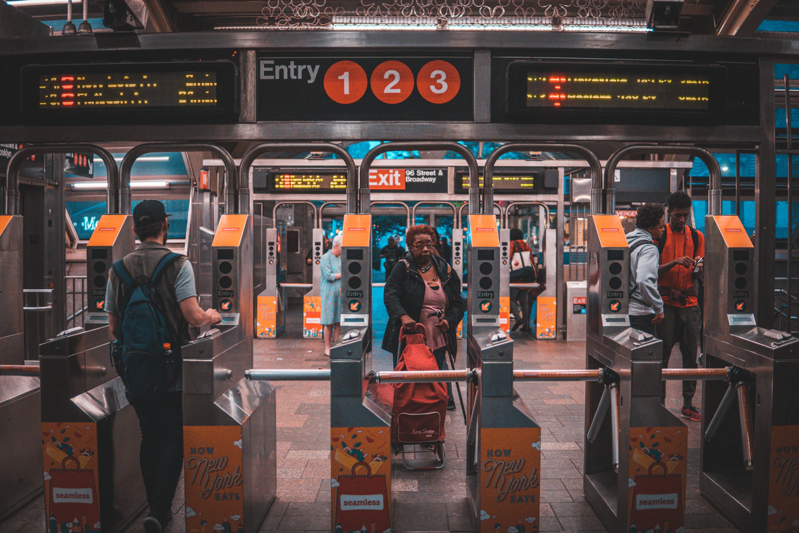 Riders passing through turnstiles at a New York subway station entrance