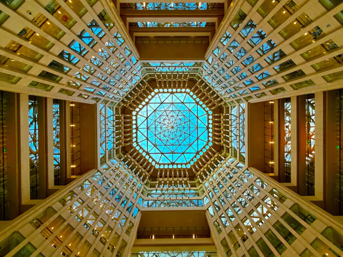 Looking up at an octagonal glass-ceilinged hotel atrium ringed with balconies