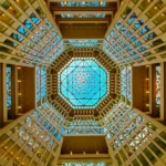 Looking up at an octagonal glass-ceilinged hotel atrium ringed with balconies