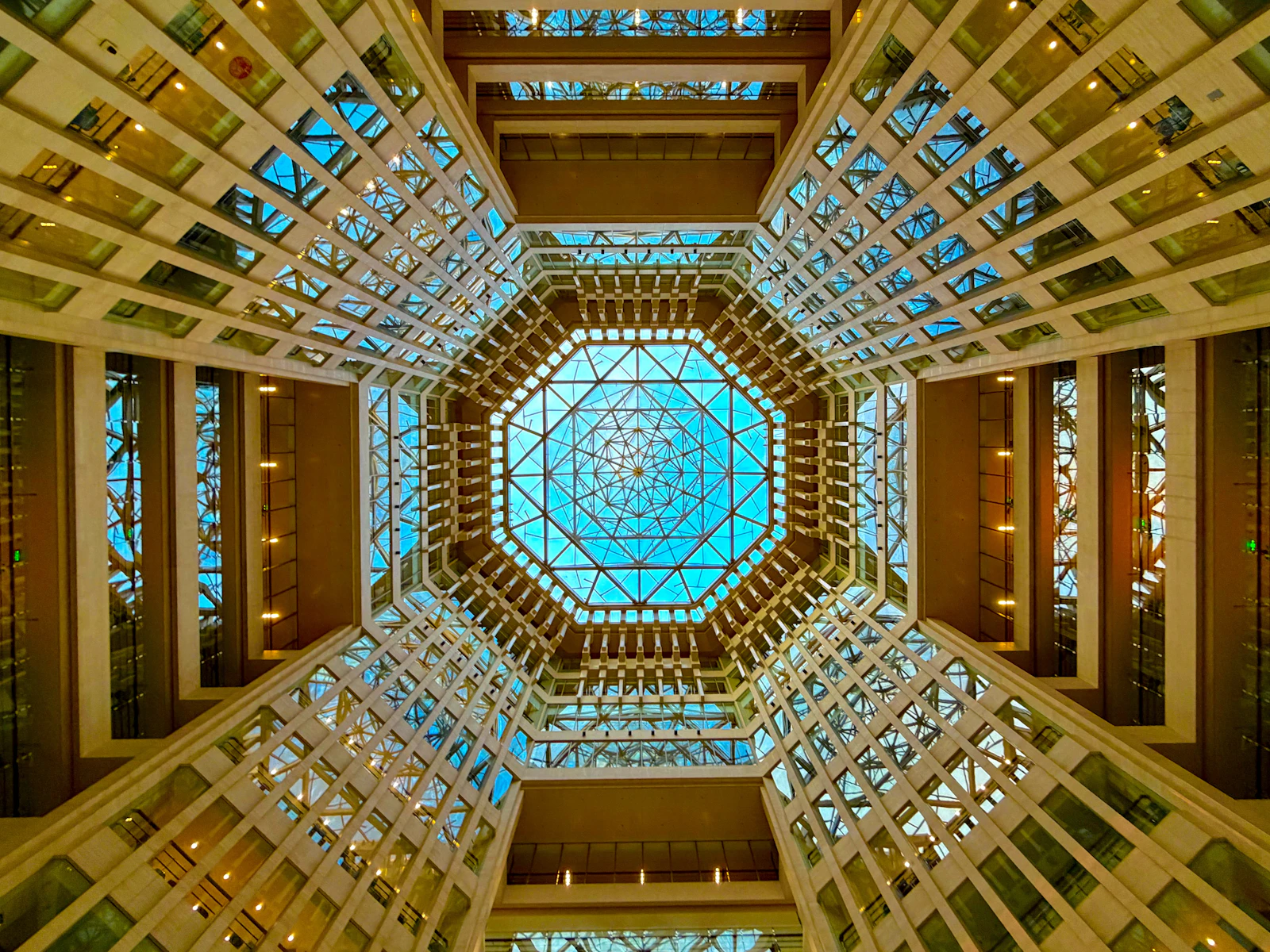 Looking up at an octagonal glass-ceilinged hotel atrium ringed with balconies