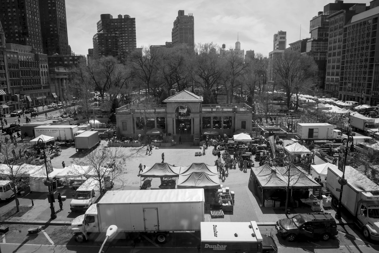 Black-and-white aerial view of market tents and delivery trucks in Union Square Park